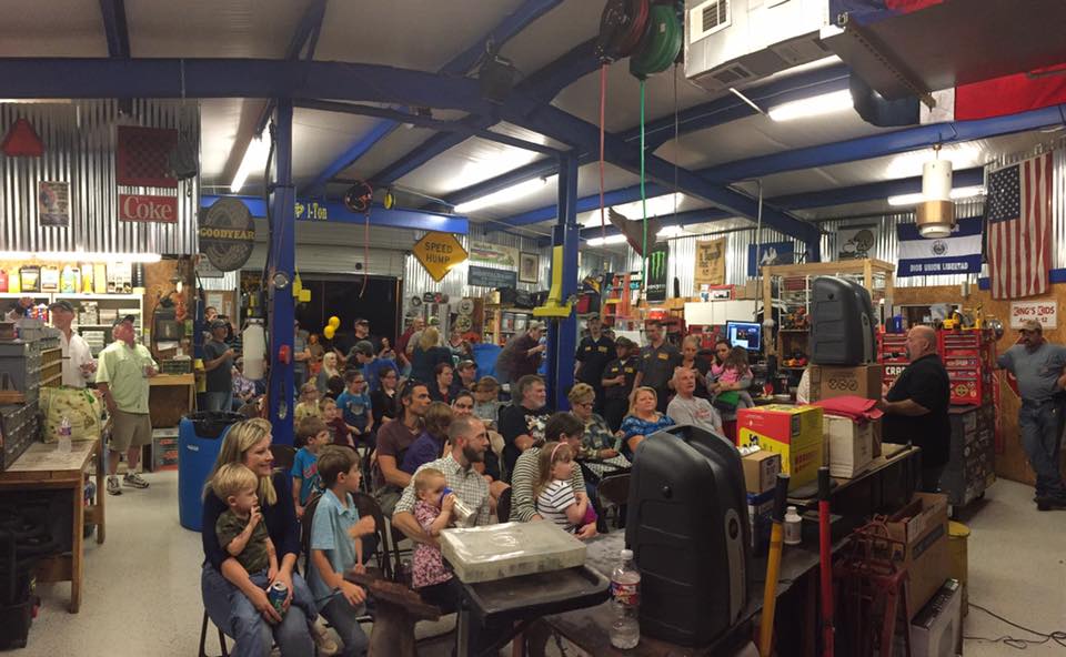 Community gathering seated in the God’s Garage shop on a light coated concrete floor