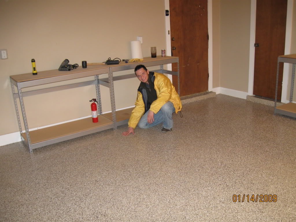 Installer in a yellow jacket kneeling on a Houston Garage Floors flake epoxy garage floor, January 14, 2009